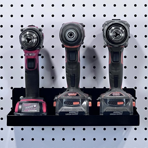 A group of Triton DuraHook black steel shelves holding three cordless drills.
