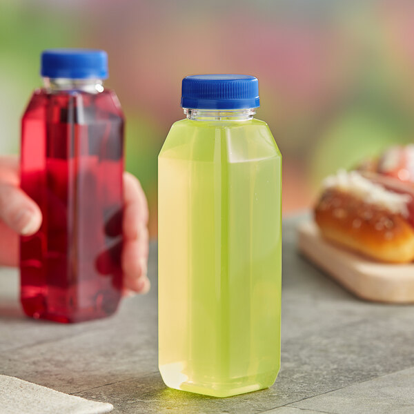 A hand holding a 10 oz. square clear PET juice bottle with blue liquid inside.