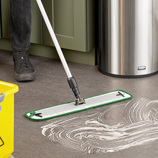 A person mopping the floor with a Lavex Green Microfiber Mop Pad on a black mop handle.