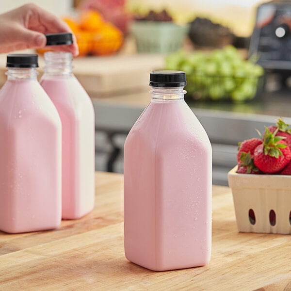 A close-up of a pink 32 oz. Square Milkman PET juice bottle with a black lid.