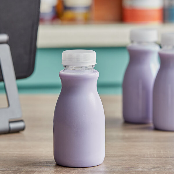 A clear PET juice bottle filled with purple liquid on a table.