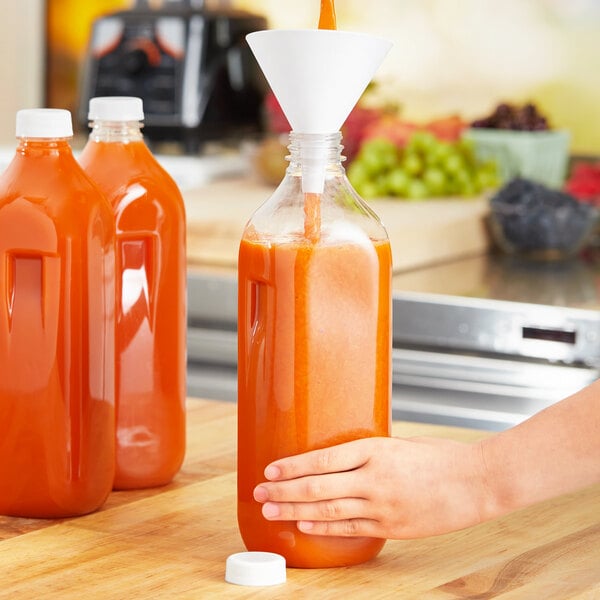 A hand pouring orange juice into a Square PET clear juice bottle.