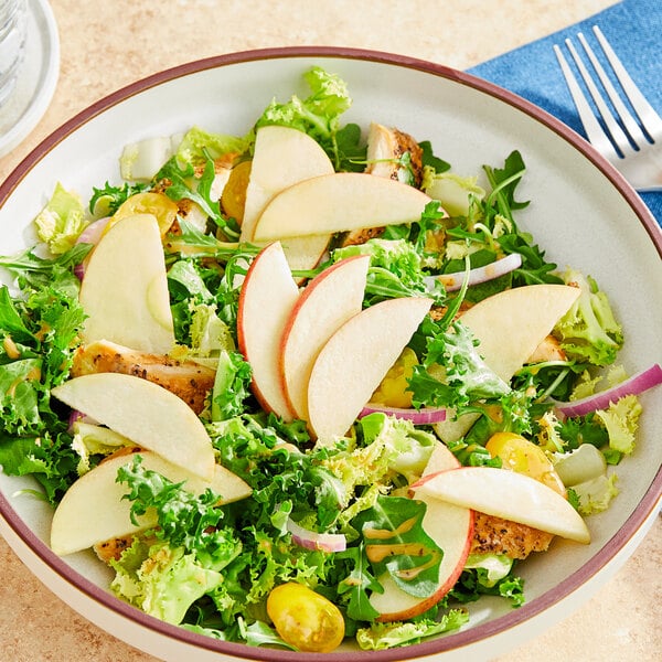 A close up of a plate of salad with sliced Fresh Fuji Apples.