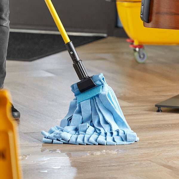 A person using a Lavex Blue Microfiber Strip Mop to clean a floor.