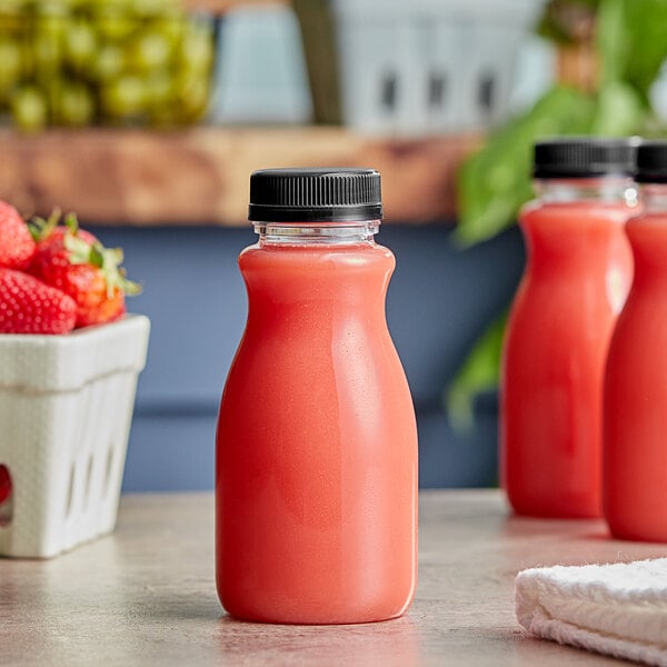 Three 8 oz. round clear juice bottles filled with red liquid with a black lid.