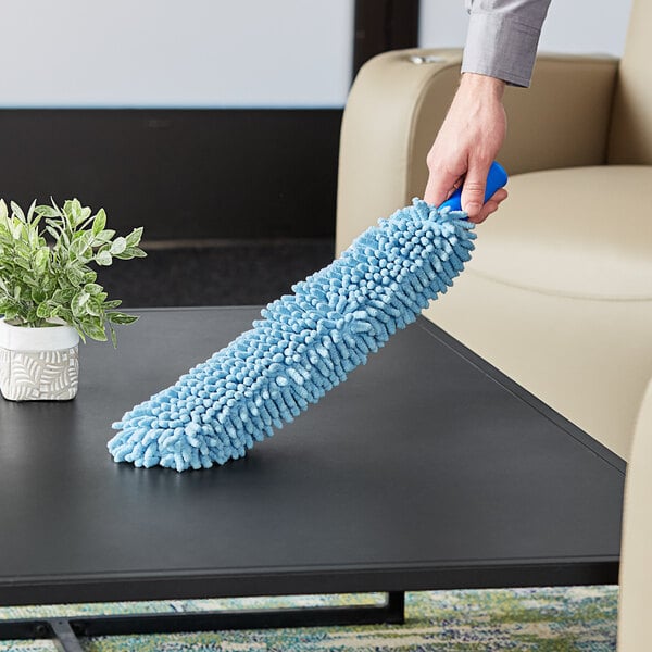 A hand holding a blue Lavex Chenille microfiber duster sleeve over a black surface.