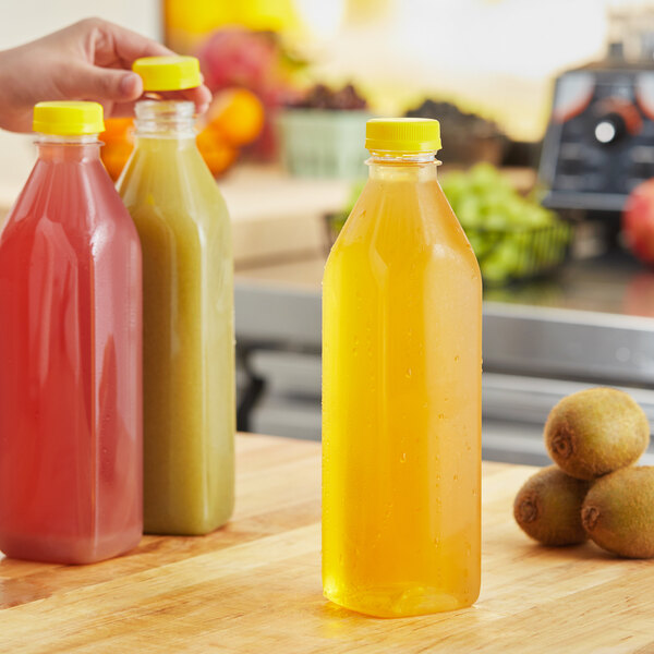 A hand holding a yellow plastic Tall Square Milkman juice bottle.