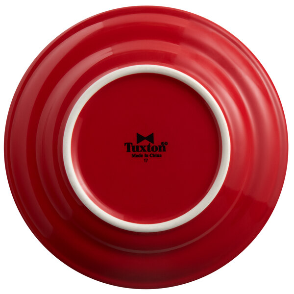 A red Tuxton Concentrix china plate with a white rim.