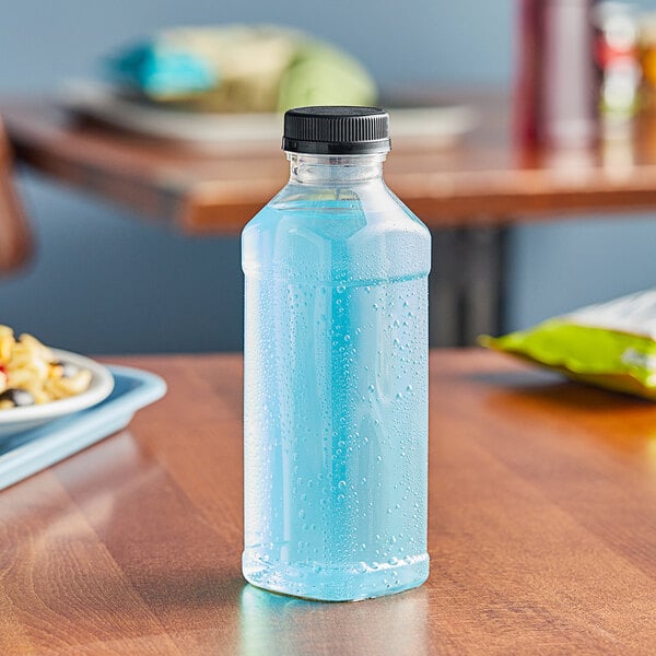 A close-up of a Square PET clear juice bottle with black lid on a table.