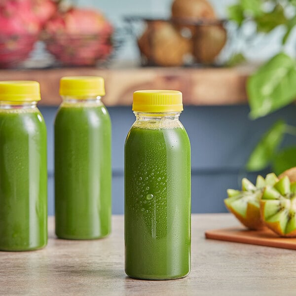 Three green juice bottles on a counter with fruit.