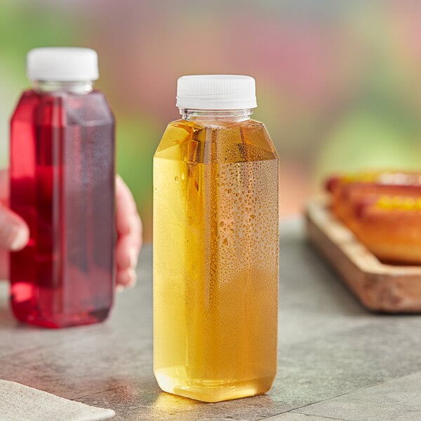 A person holding a 10 oz. square clear PET juice bottle.