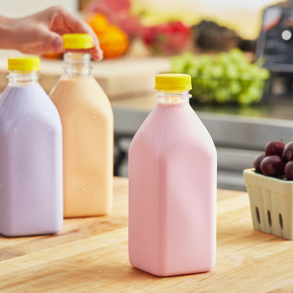 A woman holding a 32 oz. square clear PET milk bottle with a yellow lid.