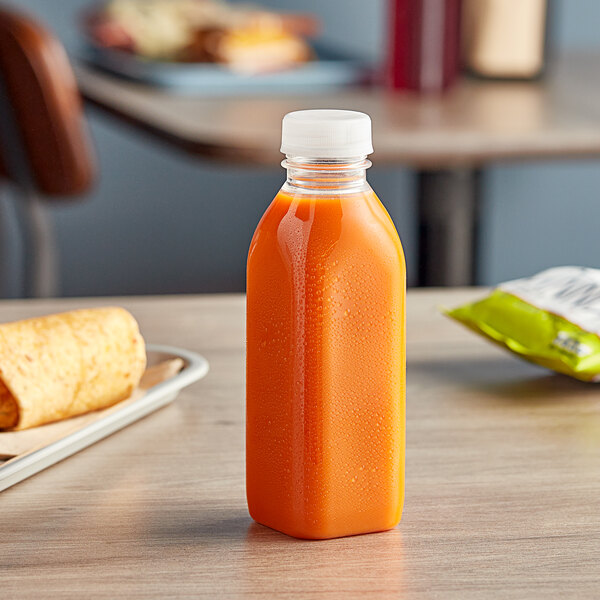 A 16 oz. square clear PET juice bottle with clear lid on a table.