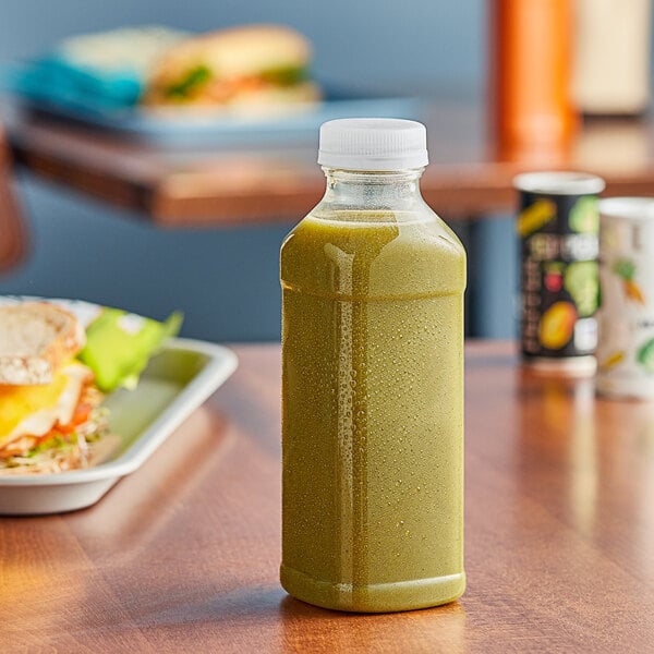 A clear Square PET juice bottle filled with green liquid on a table.