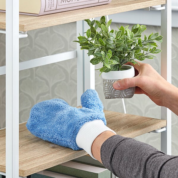 A person using a blue Lavex microfiber mitt to hold a potted plant.
