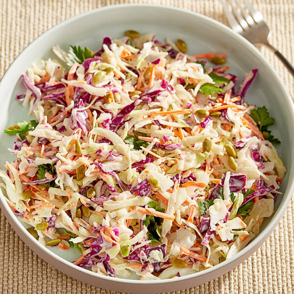 A bowl of coleslaw with a fork next to it.