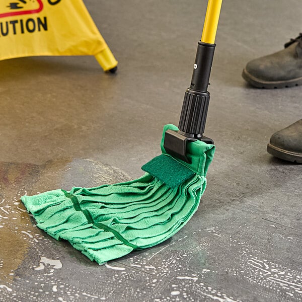 A person using a Lavex green microfiber strip mop with a green cloth to clean a floor.