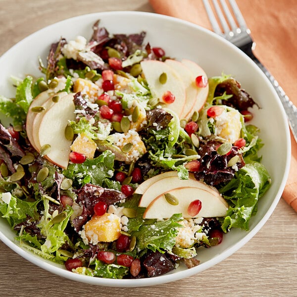 A bowl of Arcadian Harvest Salad with apples and pomegranate seeds.