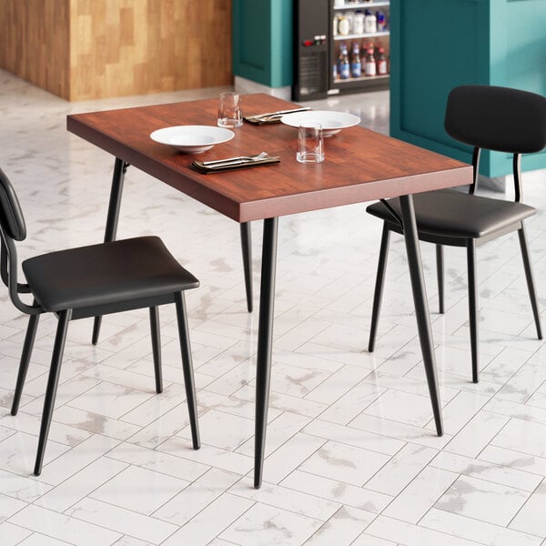 A Lancaster Table & Seating butcher block table with mahogany finish set with plates and glasses on it.