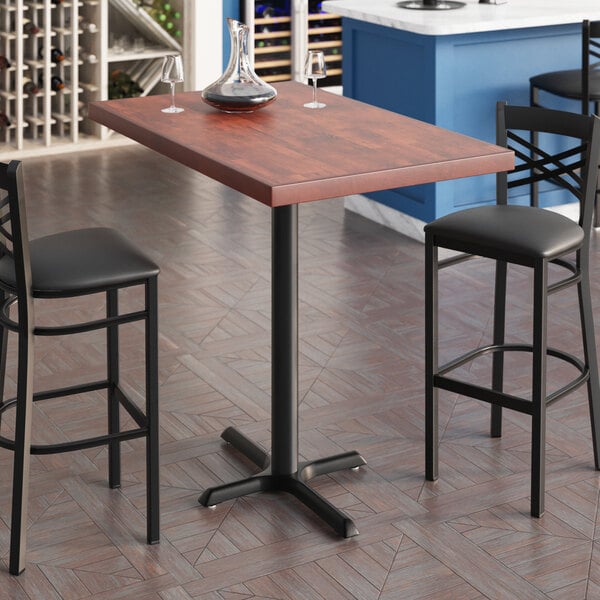 A Lancaster Table & Seating rectangular bar height table with wine glasses on it.