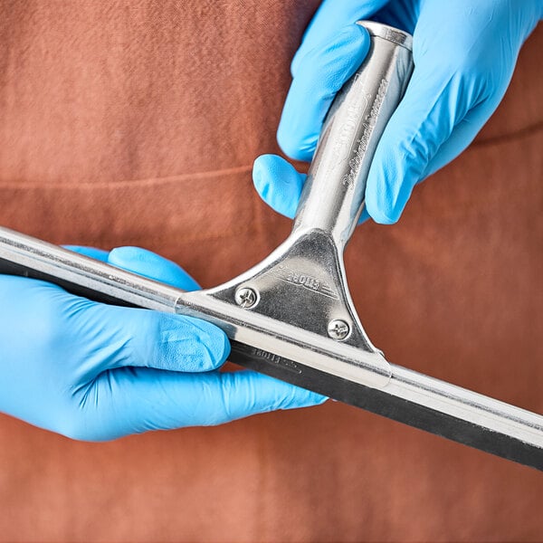 A person in blue gloves holding an Ettore aluminum squeegee handle.