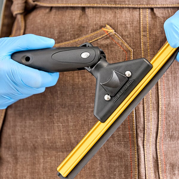 A person in blue gloves using a yellow Ettore squeegee handle.