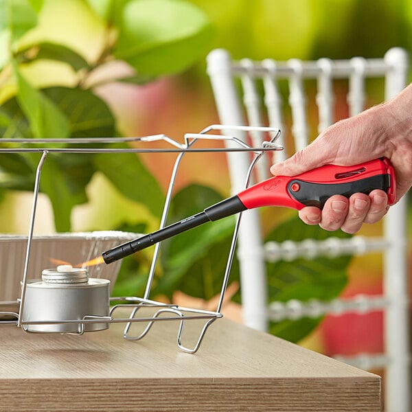 A hand using a red and black Scripto EZ-Squeeze Torch Flame Refillable Lighter.