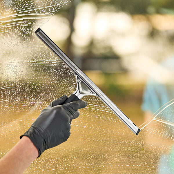 A hand in a black glove using an Ettore Master stainless steel squeegee to clean a window.