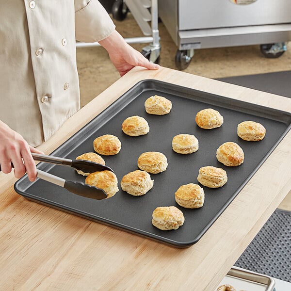 A person cutting biscuits on a Baker's Lane non-stick bun pan.