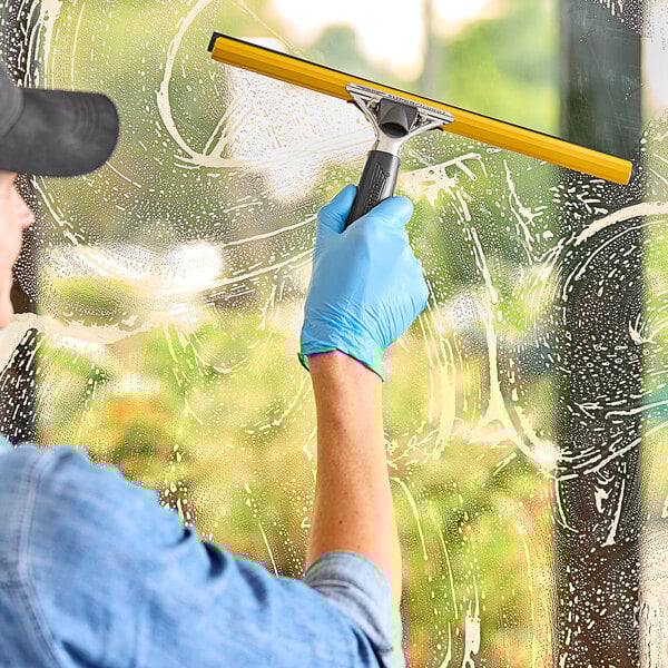 A hand using an Ettore squeegee to clean a window