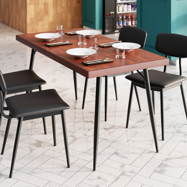 A Lancaster Table & Seating butcher block table with mahogany finish set with plates and glasses.