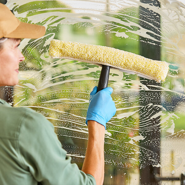 A person uses a 14-inch microfiber strip window washer sleeve to clean a soapy glass surface.