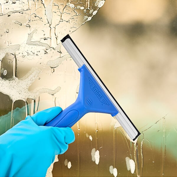 A hand in a blue glove using an Ettore blue-handled squeegee to clean a window.