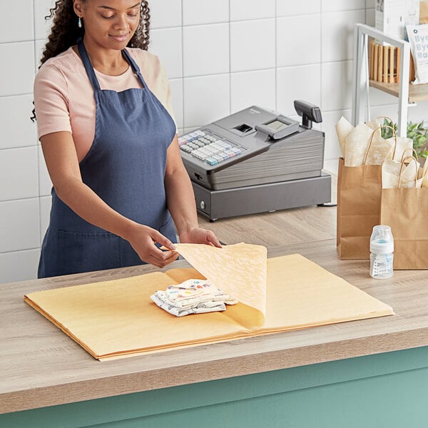 A woman wearing an apron holding SatinWrap Backyard Blossoms tissue paper sheets.