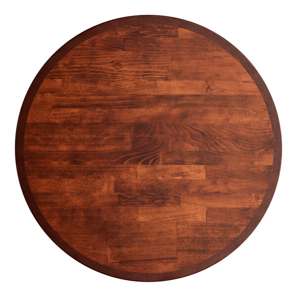A Lancaster Table & Seating round wooden table top with a mahogany finish on a table.