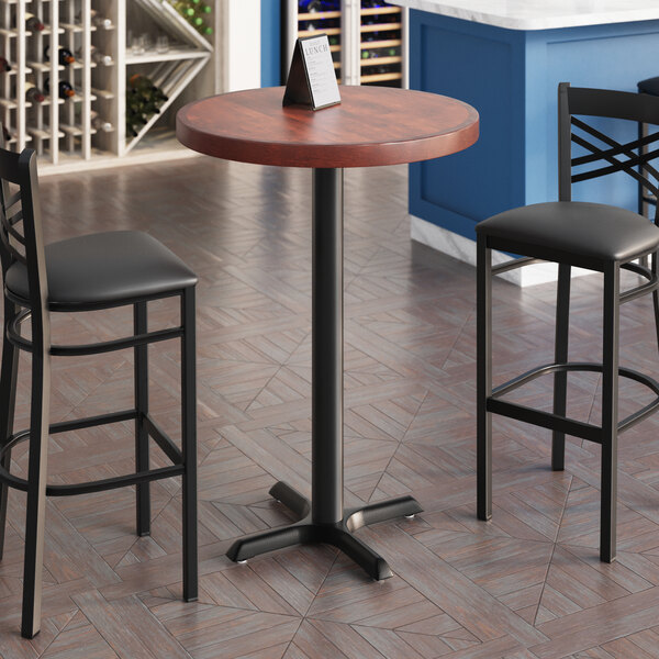 A Lancaster Table & Seating round butcher block table with mahogany finish and cast iron base plate.