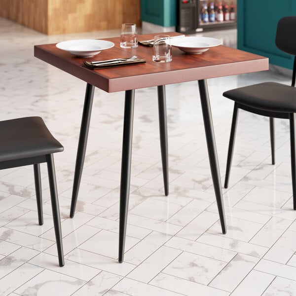 A Lancaster Table & Seating butcher block table with mahogany finish, set with plates and glasses.