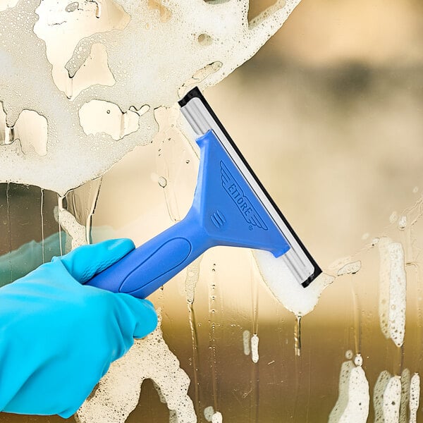 A hand wearing a blue glove using an Ettore 6" squeegee to clean a window.