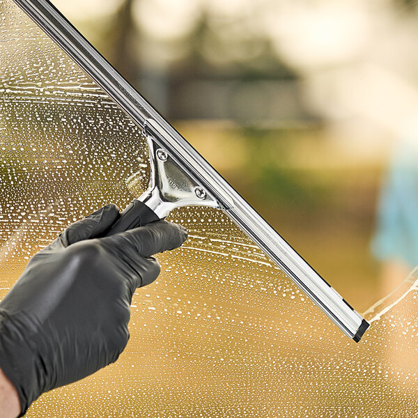 A hand in a black glove using an Ettore Master stainless steel squeegee to clean a window.