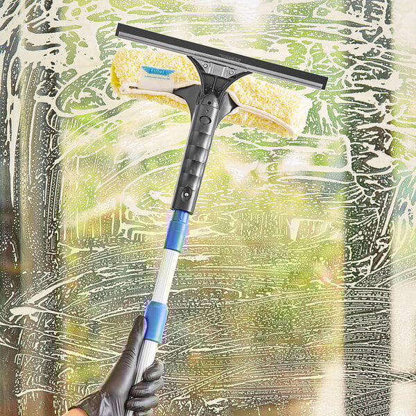 A hand holding an Ettore squeegee to clean a window.