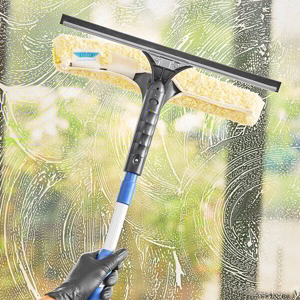 A hand using an Ettore squeegee to clean a window.