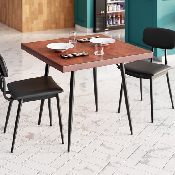 A Lancaster Table & Seating butcher block table with a mahogany finish set with plates and glasses.