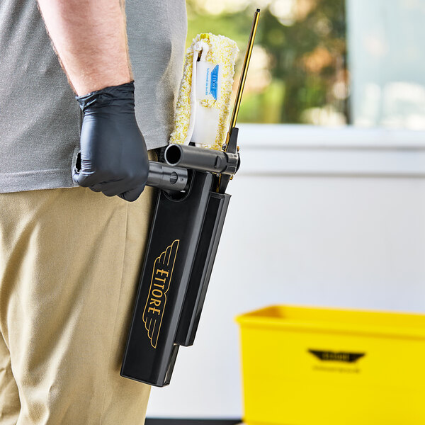 A man wearing a black Ettore SideKick holster and holding a window cleaning tool.