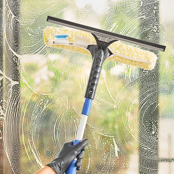 A hand using an Ettore Backflip squeegee to clean a window.