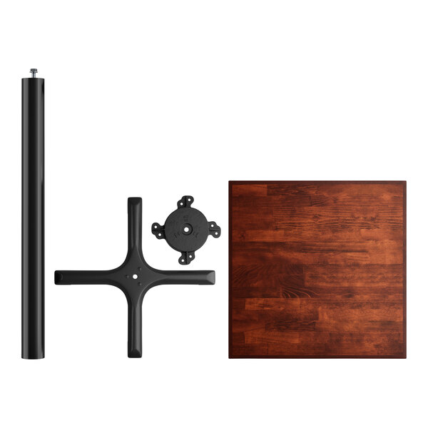 A Lancaster Table & Seating bar height table with a mahogany wood butcher block top and black cast iron base plate with a cross-shaped design.