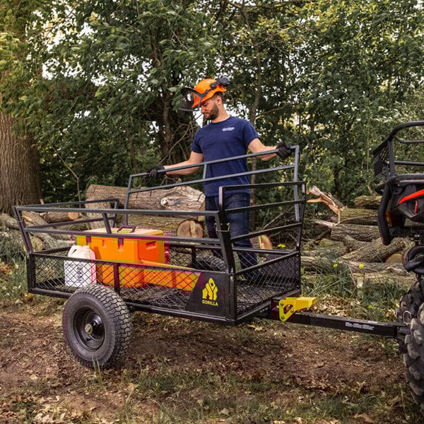 A man pushing a Gorilla heavy-duty steel ATV trailer with a utility cart in it.