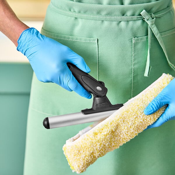 A person wearing a blue glove using an Ettore T-Bar window washer.