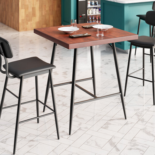 A Lancaster Table & Seating Mid-Century bar table with plates and utensils on it.