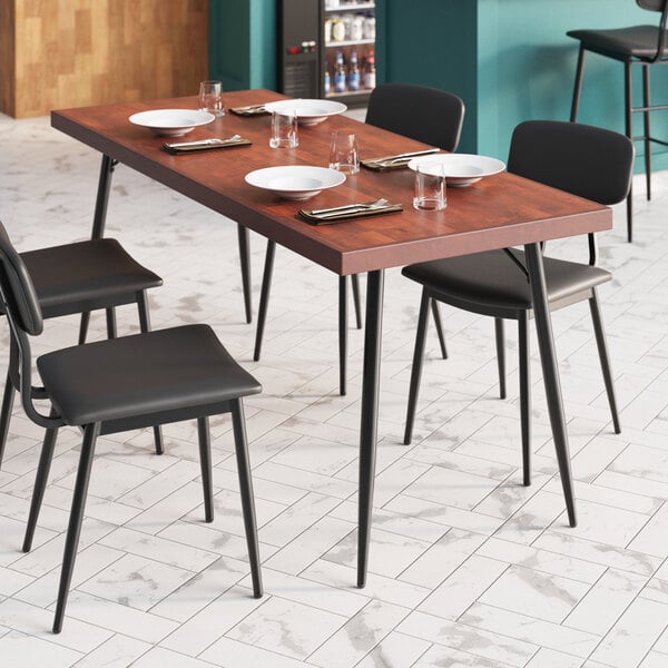 A Lancaster Table & Seating butcher block table with chairs, plates, and forks.