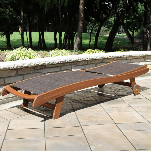 An Outdoor Interiors wooden Eucalyptus chaise lounge on a patio.